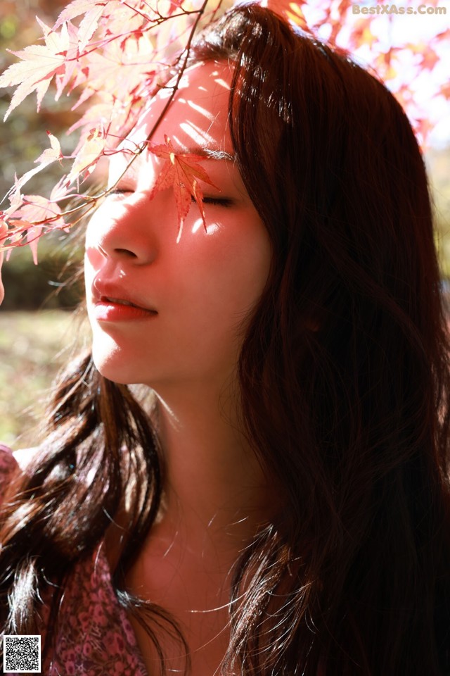 A woman with long brown hair and a pink flower in her hair.