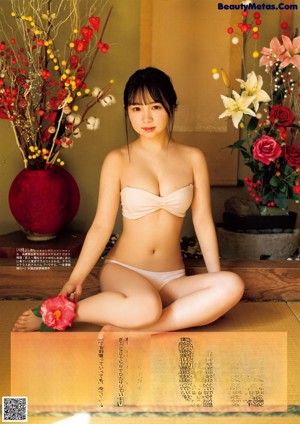 A woman in a white bikini with a flower in her hair.