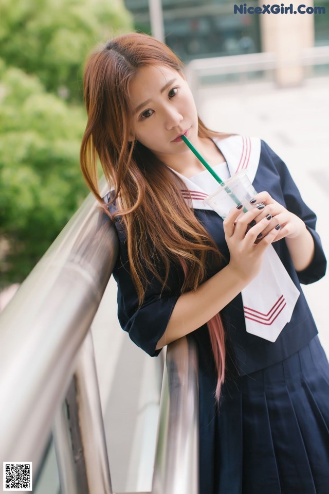 A woman in a school uniform drinking from a straw.