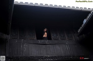 A naked asian woman sitting in a stone bowl of water.