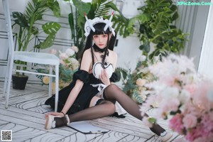 A woman dressed as a maid sitting on a chair.