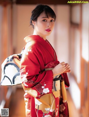 A woman in a red kimono sitting on the floor.