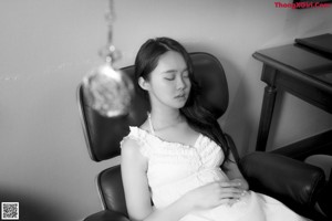 A woman in a white lingerie laying on a chair.