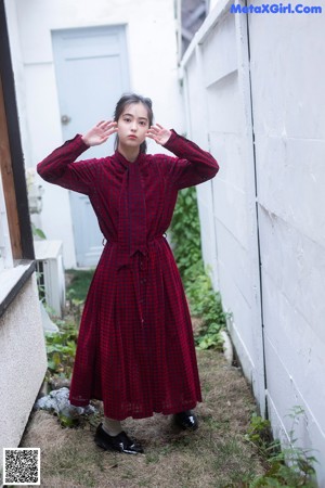 A woman in a red dress sitting on a brick walkway.