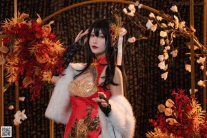 A woman in a red and black outfit sitting on a rock.