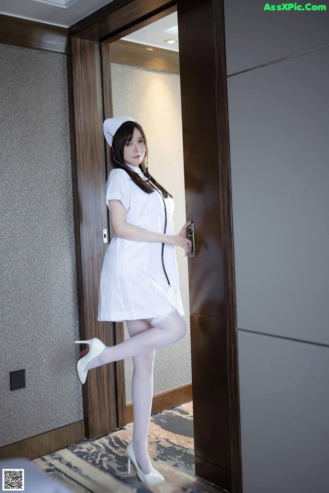 A woman dressed as a nurse standing in front of a door.