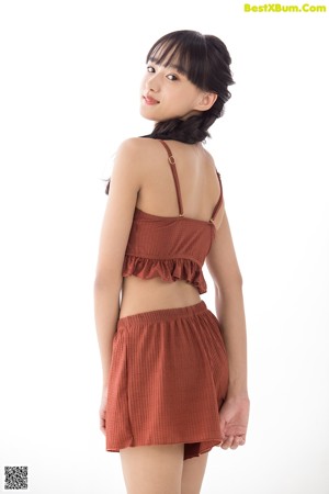 A woman leaning against a white wall with her hands on the wall.