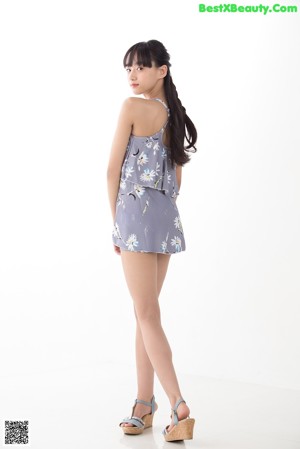 A young woman leaning against a white wall.