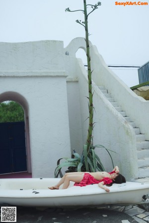 A woman in a white thong standing in front of a blue door.