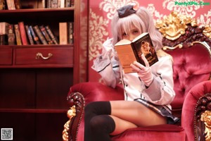 A woman sitting on a red chair holding a book.