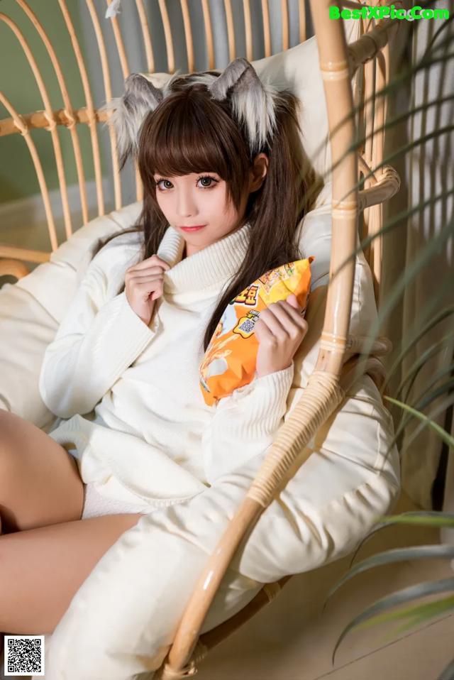 A woman sitting in a chair holding a bag of chips.