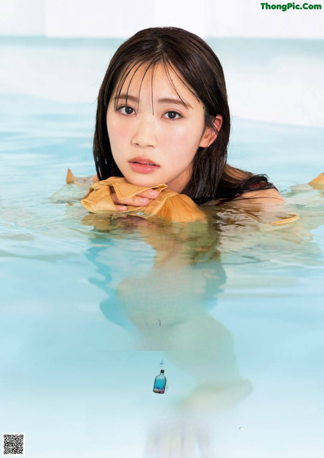 A woman in a swimming pool with a towel around her neck.