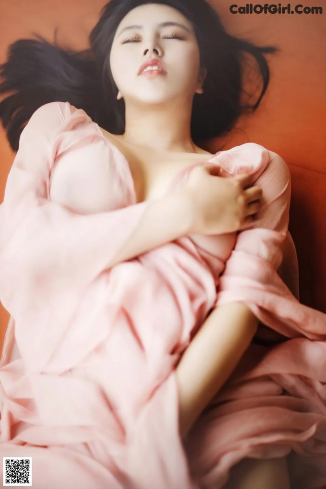 A woman in a pink dress laying on a bed.