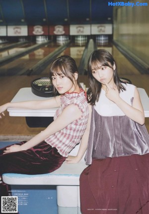 Two young women standing next to each other on a sidewalk.