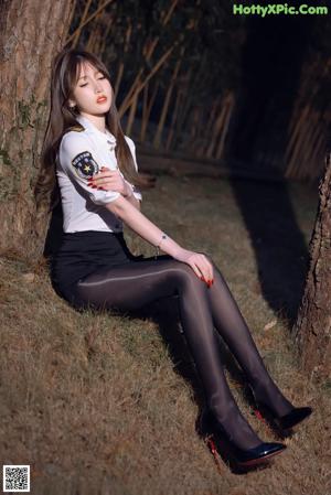 A woman in a white shirt and black stockings is sitting on a bed.