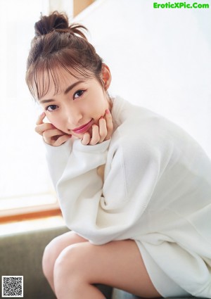 A woman in a blue sweater sitting on a brown chair.