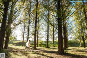 A woman in a white dress standing in a park.