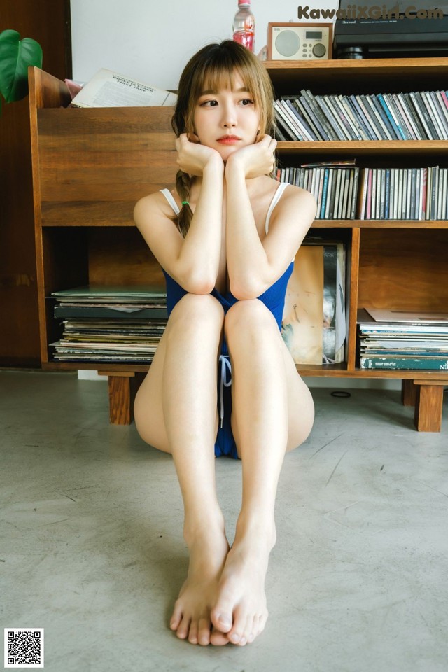 A woman in a blue bathing suit sitting on the floor.