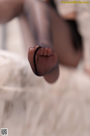 A woman in a white shirt and black pantyhose leaning against a door.