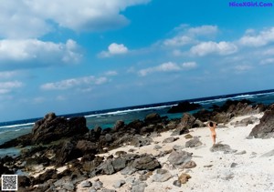 A woman in a black swimsuit standing on a beach.