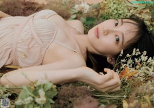 A woman laying on the ground surrounded by flowers.