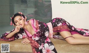 A woman in a pink and black kimono sitting on the floor.