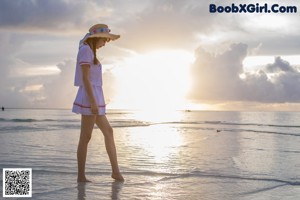 A woman in a white bikini and a straw hat on the beach.