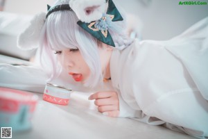 A woman in a white shirt and white stockings is posing on a bed.