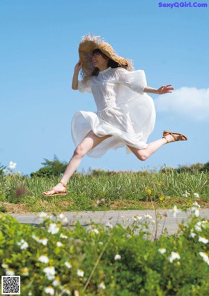 A woman in a white dress standing on a rock.