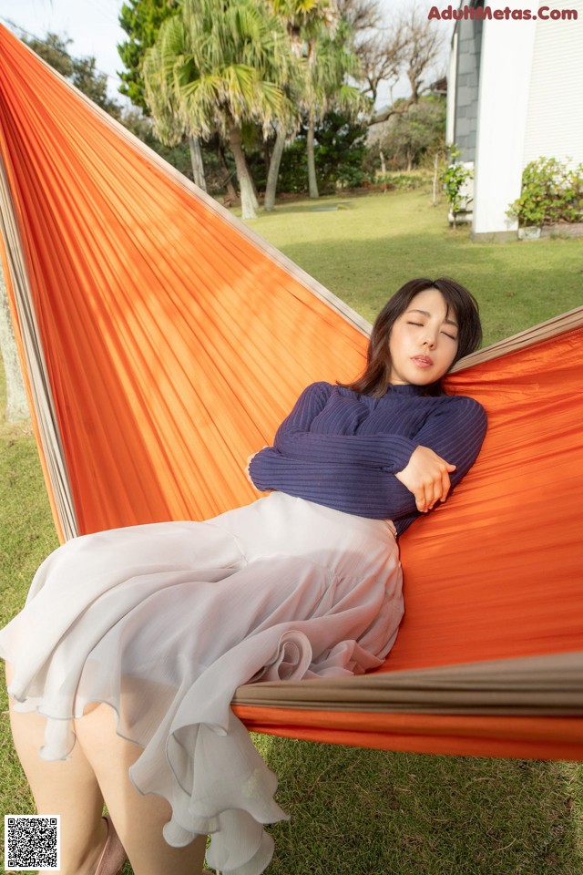 A woman laying in a hammock in the grass.