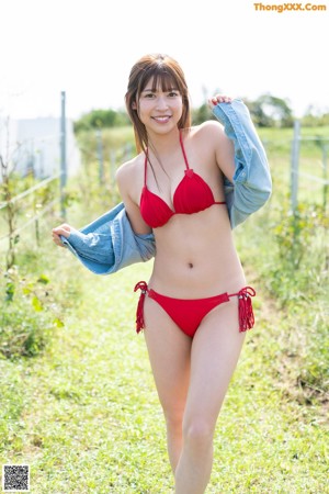 A woman in a blue bikini standing next to a door.