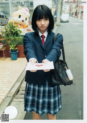 A woman in a school uniform holding a piece of paper.