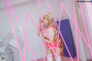 A woman in a pink and white outfit sitting on a pink floor.