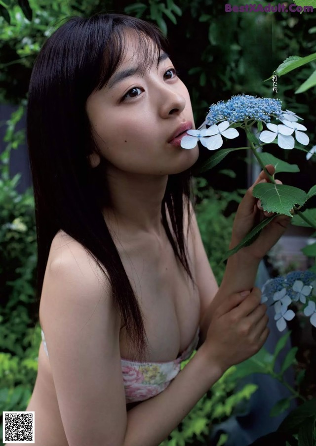 A naked woman holding a blue flower in her hand.