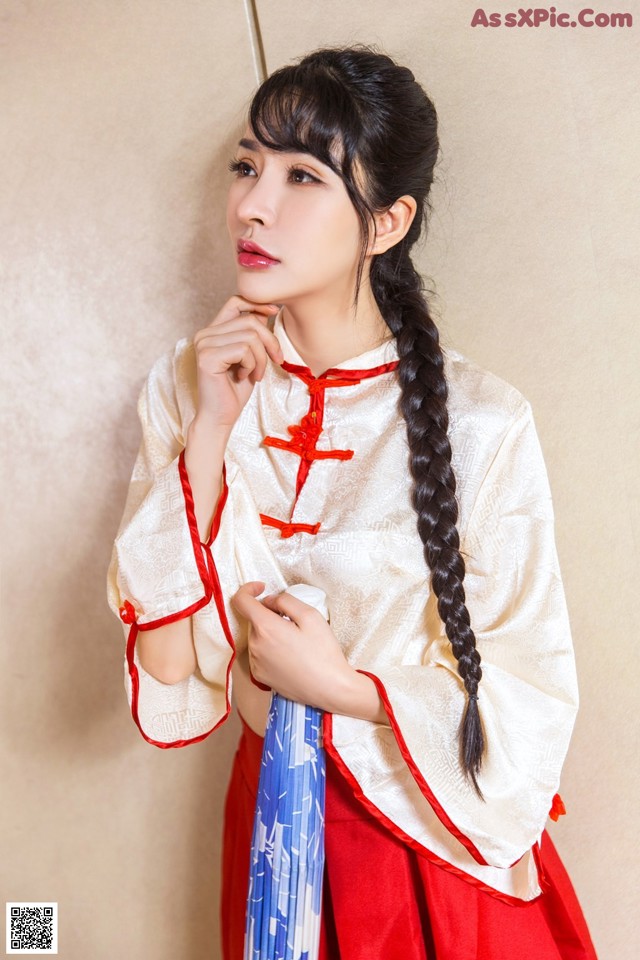 A woman in a red and white dress holding a blue umbrella.