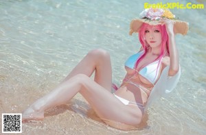 A woman with pink hair wearing a white bikini and a straw hat.