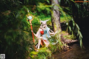 A woman in a green dress holding a wand in the water.