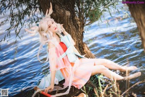 A woman sitting on a tree branch in the water.