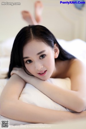 A woman sitting on a bed wrapped in a towel.