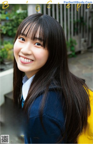 A woman in a white shirt leaning against a wooden wall.