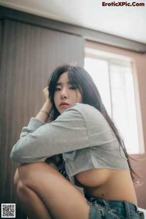 A woman laying on top of a bed next to a window.