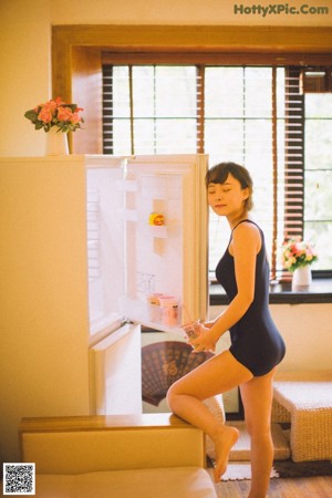 A woman sitting on a stool in front of a window.