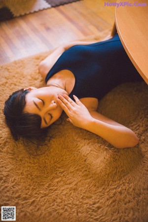 A woman in a kimono sitting on a bed holding a fan.