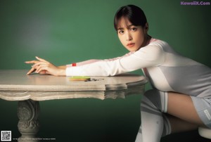 A woman sitting on top of a table next to a stack of books.