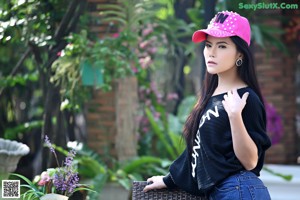 A woman wearing a pink hat sitting on a bench.