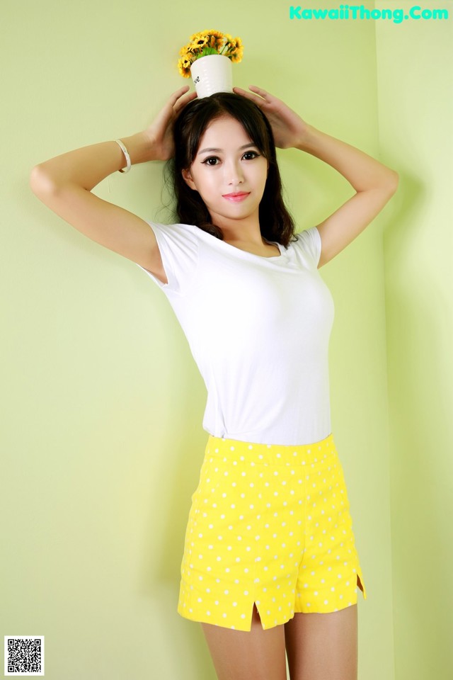 A woman in a white shirt and yellow polka dot shorts.