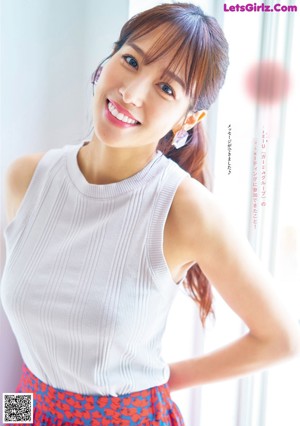 A woman in a white top and red skirt posing for a magazine.