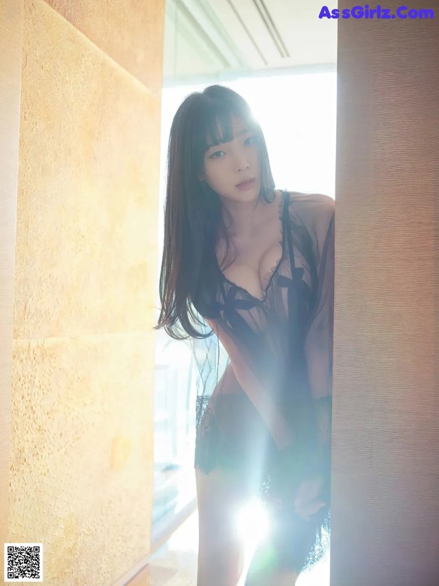 A woman in a black lingerie leaning against a wall.