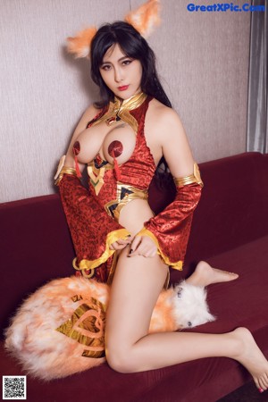 A woman in a fox costume sitting on a red couch.