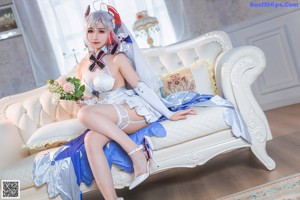 A woman in a white dress sitting on a white couch.